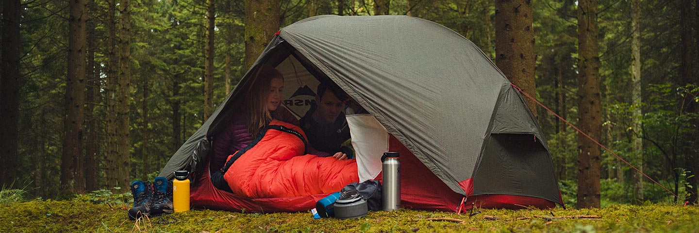 woman in tent pitched in woodland